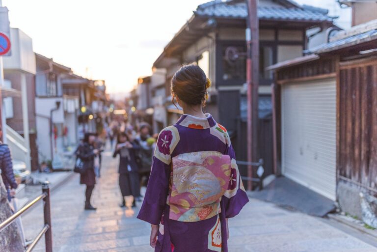 En kvinne i kimono går bortover en gammel gate